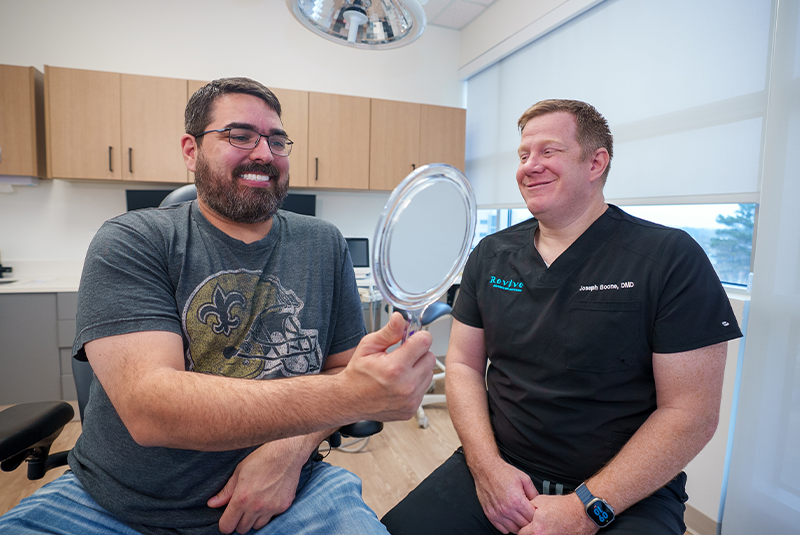 Dr. Boone and his patient holding a mirror smiling